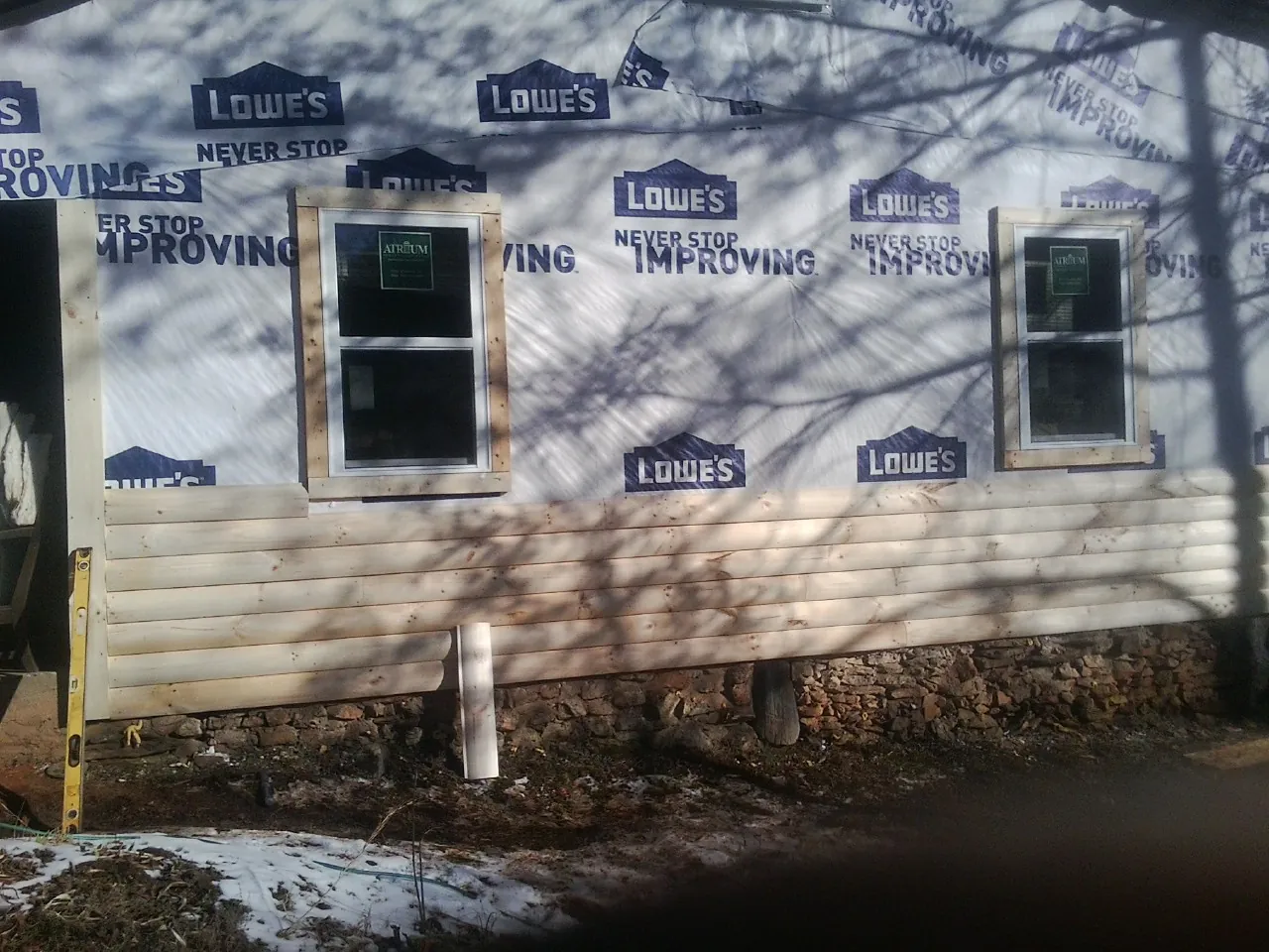 House wrap and new log siding going up on an exterior wall in Lumberville