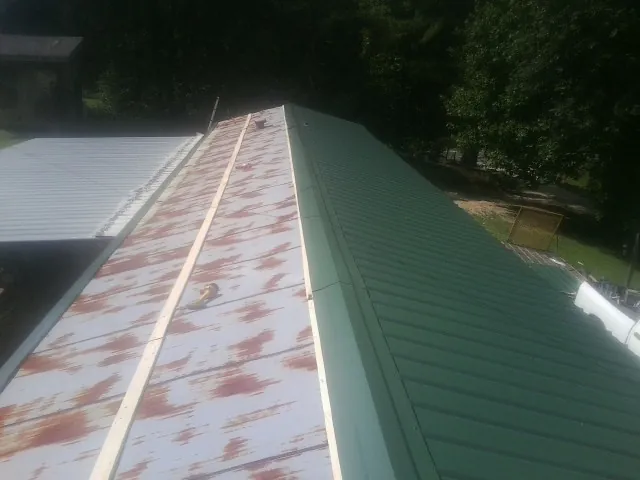 Old rusted panels beside newly installed green metal roofing — Wind Damage Roof Repair by Roofing Brothers in Lumberville