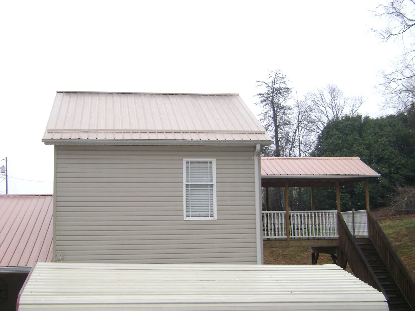 Tan metal roofs on a two story addition and attached porch, from a Roof Replacement job in Lumberville