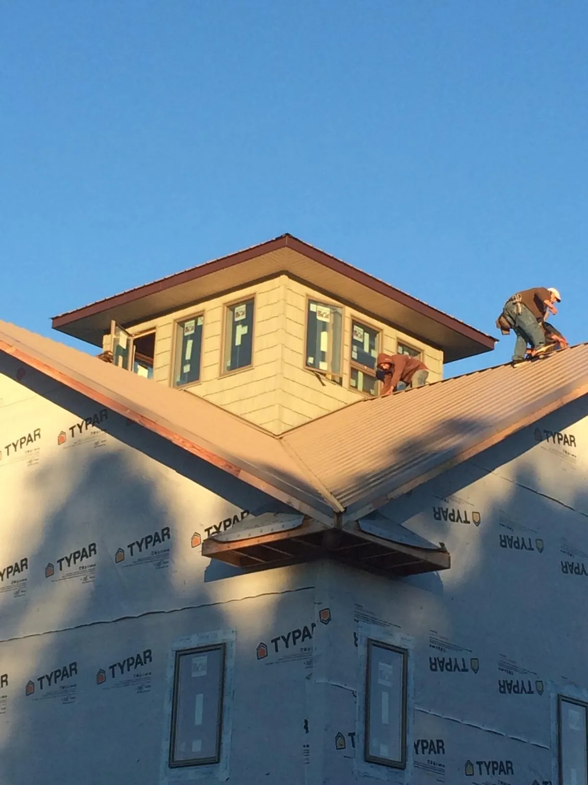 Roofers working around a rooftop cupola on a new metal roof at sunset — Roof Waterproofing in Lumberville by Roofing Brothers